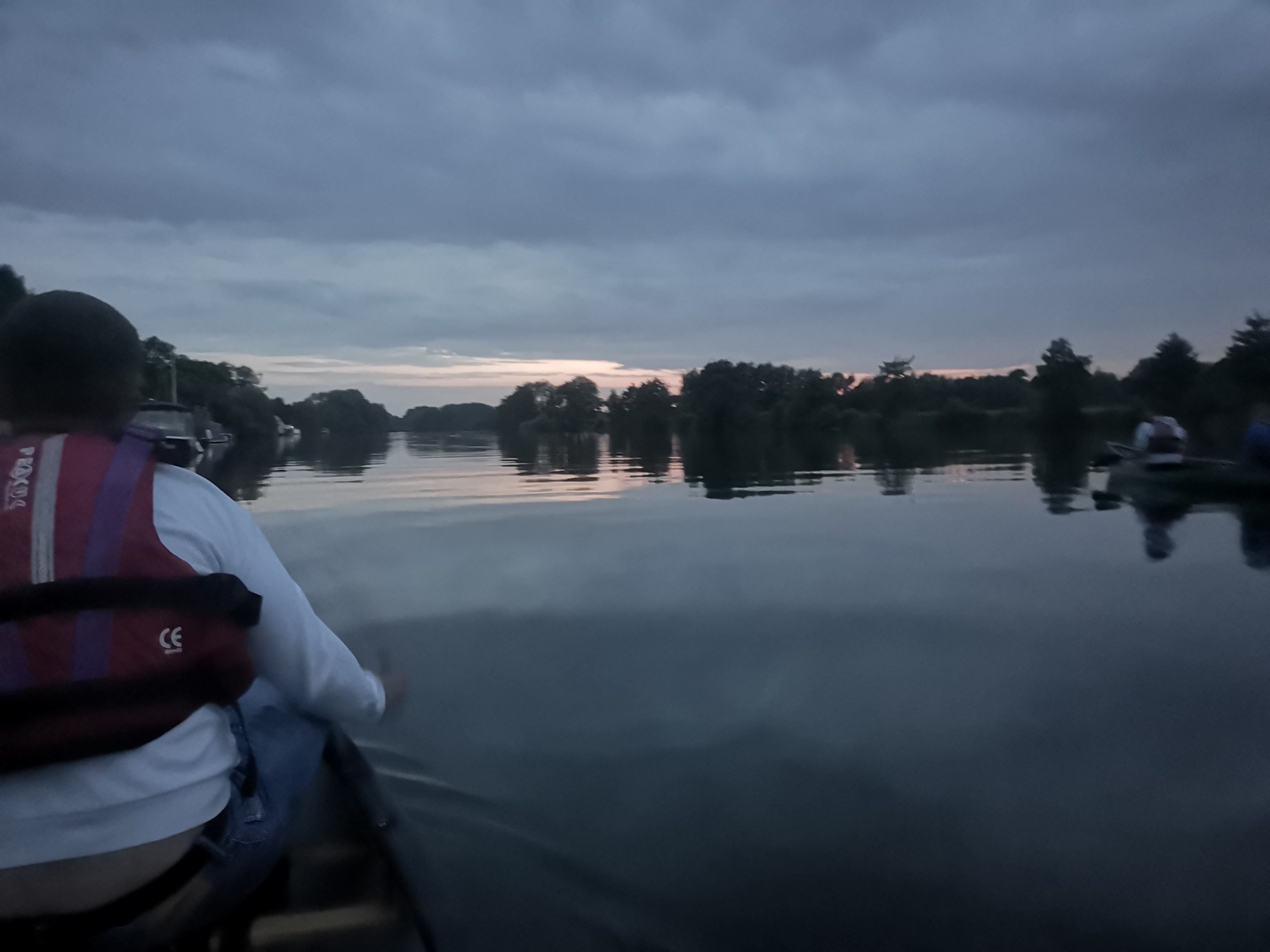 Peaceful evening paddle on calm river with wooded shores at dusk