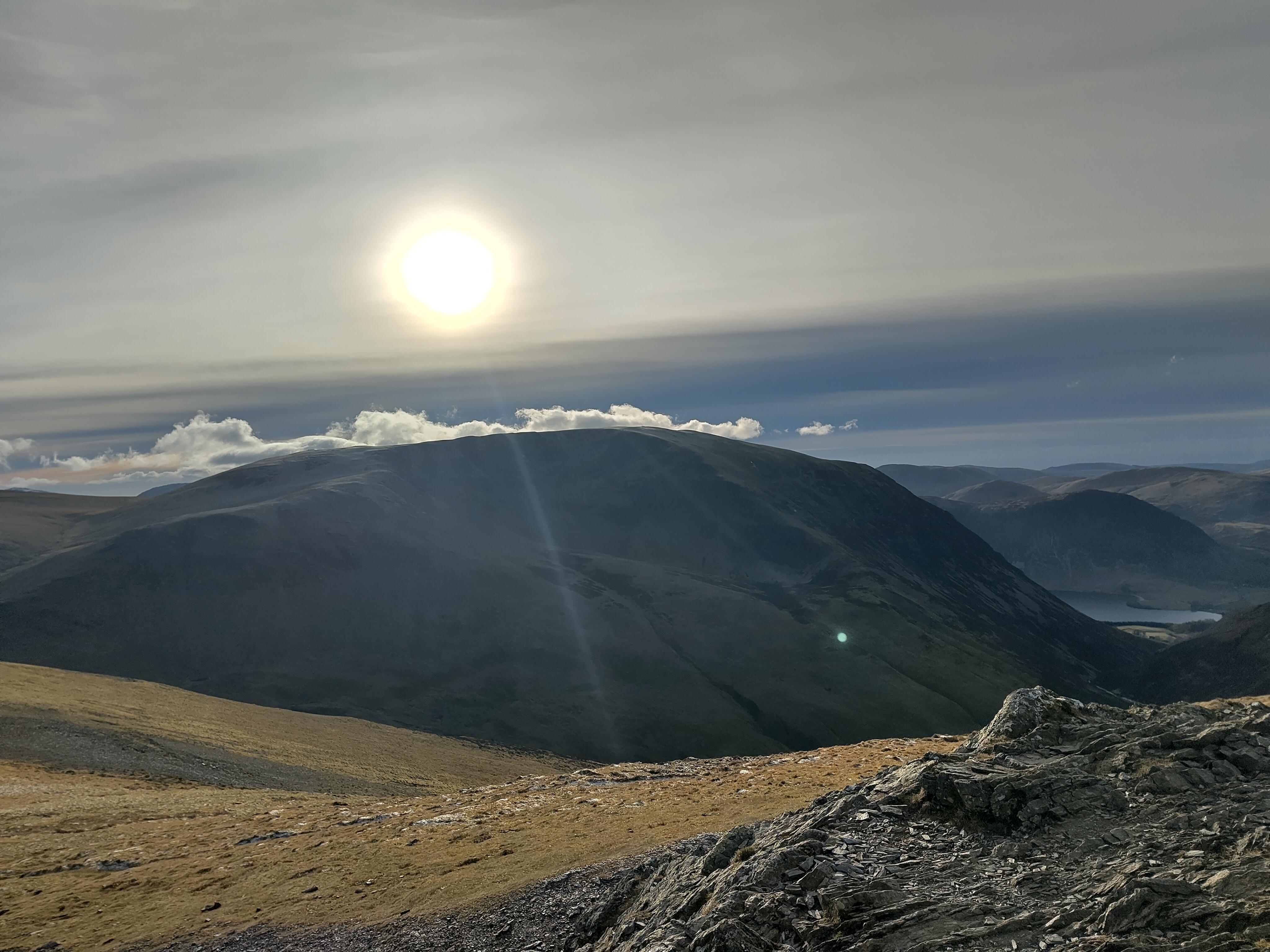 Dramatic mountain ridge silhouette with sun breaking through clouds
