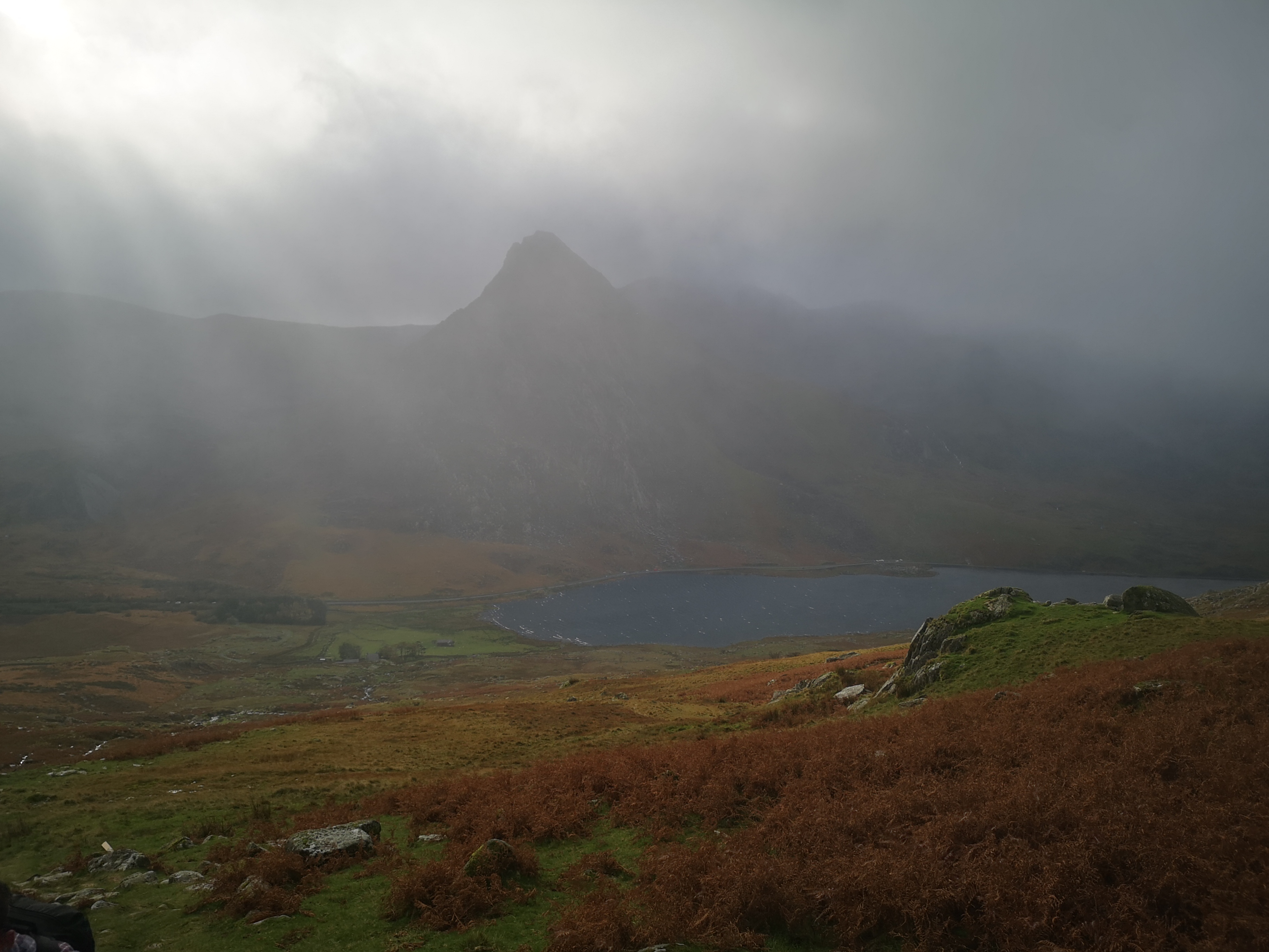 Misty valley view with loch and mountain silhouette shrouded in fog